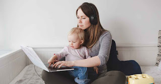 Woman working from home on a laptop while balancing career and family responsibilities.