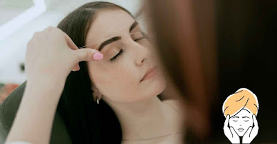 A woman receiving a threading beauty service at home